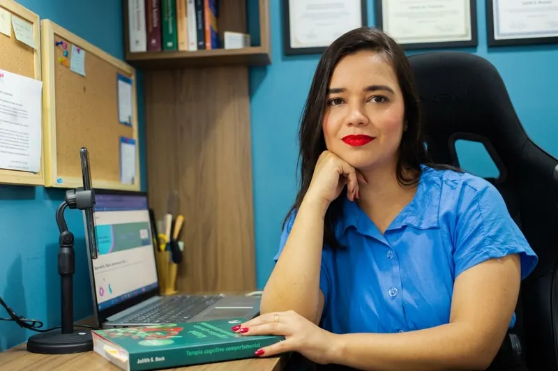 Daiane Alcantara em seu consultório, cercada de livros de psicologia